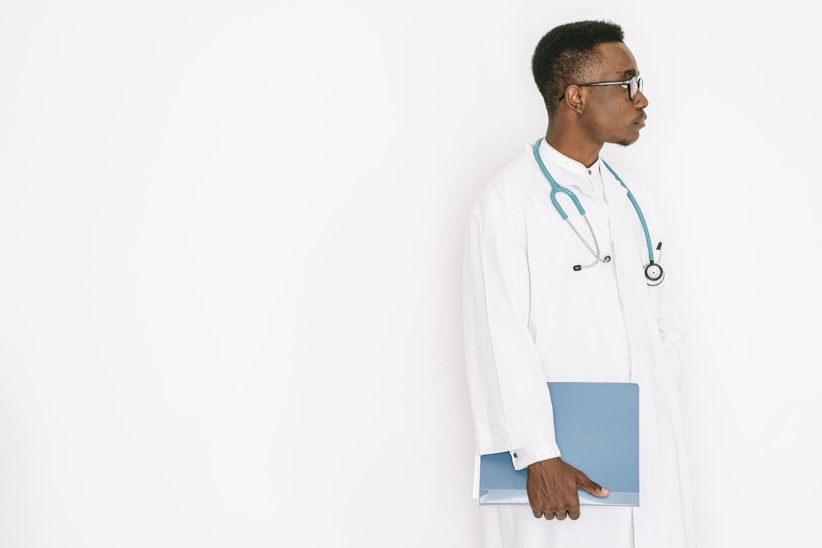 A health worker in a white coat holding a folder.